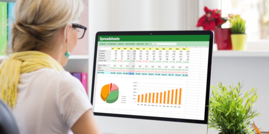 Young office worker working with data and graphs in spreadsheet document on desktop computer